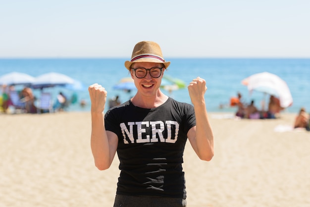 Retrato de jovem turista bonito como nerd na praia na Espanha