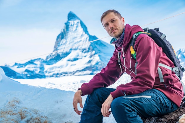 Retrato de jovem turista sentado na rocha contra a montanha Matterhorn no inverno