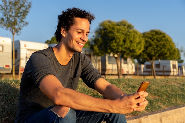 Foto retrato de jovem usando o celular no parque com um belo pôr do sol