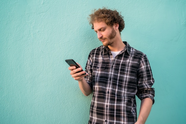 Retrato de jovem usando seu telefone celular contra um fundo azul. Conceito de comunicação.