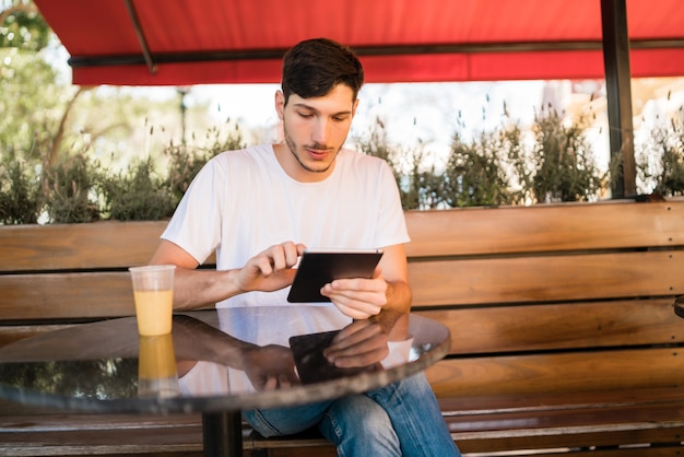 Retrato de jovem usando um tablet digital enquanto está sentado em uma cafeteria.