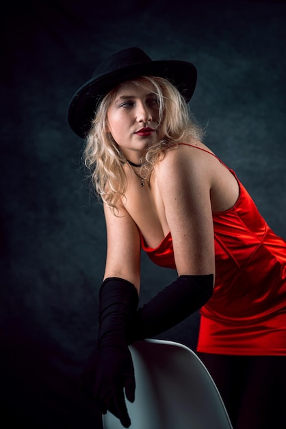 Retrato de jovem usando vestido vermelho e chapéu isolado em fundo escuro