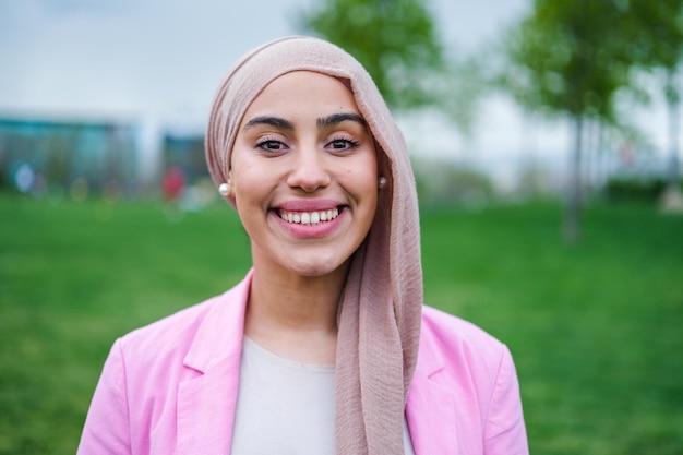 Retrato de jovem vestindo hijab e sorrindo feliz ao ar livre