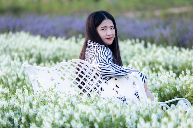 Retrato de jovem viajante asiático feliz com vestido padrão preto e branco desfrutando no campo de flores desabrochando branco no jardim da natureza em Thailandtravel relaxar férias