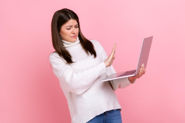 Retrato de jovem virando o rosto da tela do laptop e mostrando o conteúdo proibido do gesto de parada