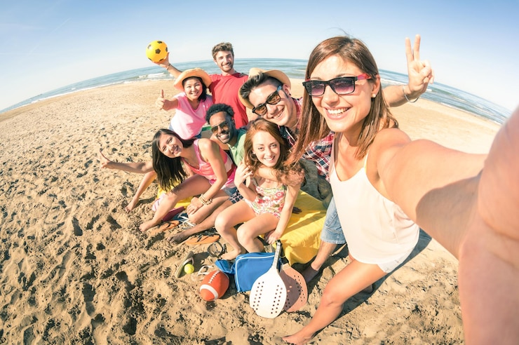 Foto retrato de jovens amigos sorridentes tirando uma selfie na praia em um dia ensolarado