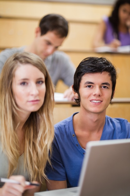 Retrato de jovens estudantes posando com um laptop