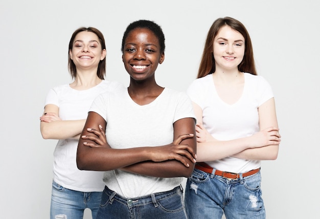 Retrato de jovens mulheres multirraciais juntos e sorrindo para a câmera isolada sobre fundo branco