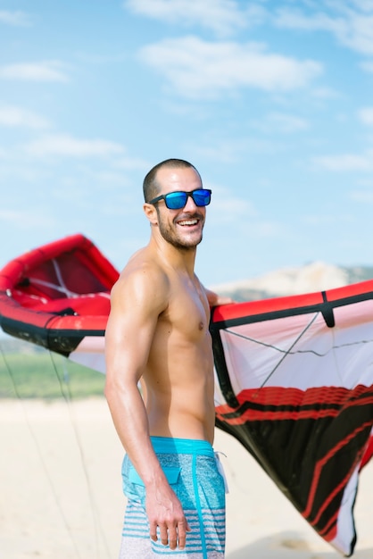 Retrato de kitesurfer de homem bonito na praia.