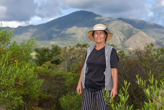 Retrato de latina fazendeira no campo com arbustos e montanhas ao fundo