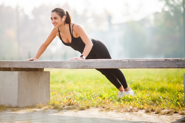 Retrato de linda mulher desportiva no sportswear fazendo flexões