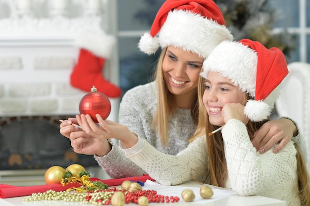 Retrato de lindas irmãs felizes se preparando para o Natal