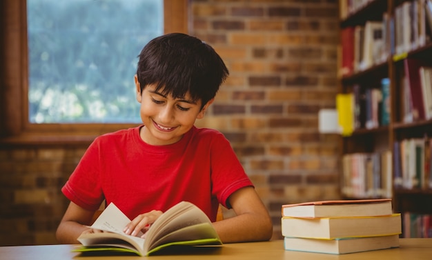 Retrato de livro de leitura de menino bonito na biblioteca