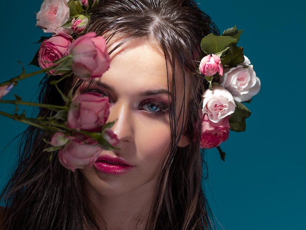 Retrato de luxo de uma bela jovem com rosas e maquiagem brilhante fresca estilo náutico azul ba...