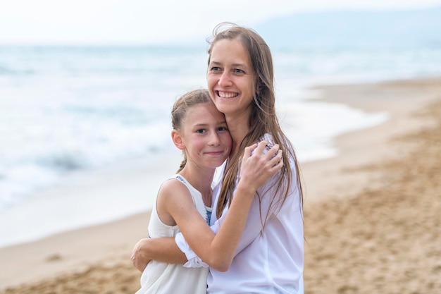 Retrato de mãe com filha de pé na praia