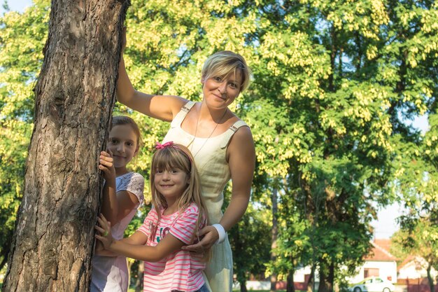 Retrato de mãe com filhos de pé contra árvores no parque