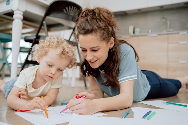 Retrato de mãe com sua filha pré-escolar passando seu tempo livre desenhando juntos enquanto está sentado