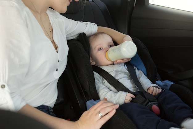 Foto retrato de mãe dando leite ao bebê no banco de trás do carro