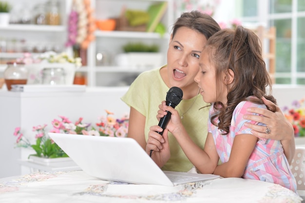 Retrato de mãe e filha cantando karaokê com microfone juntos