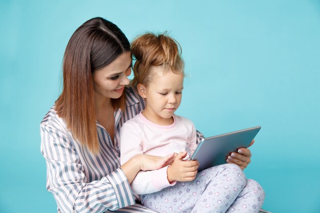 Foto retrato de mãe e filha de pijama com tablet