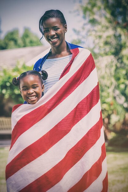 Retrato de mãe e filha embrulhados na bandeira americana no parque