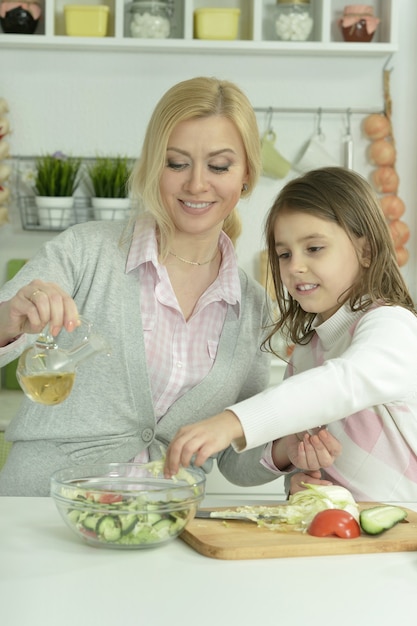 Retrato de mãe e filha felizes cozinhando na cozinha