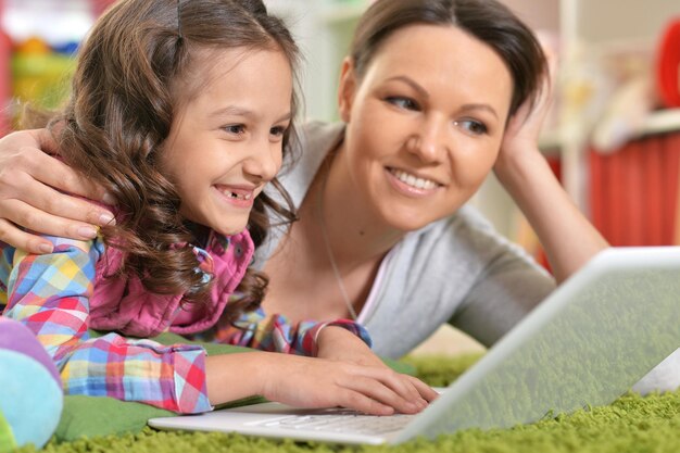 Retrato de mãe e filha felizes usando laptop em casa