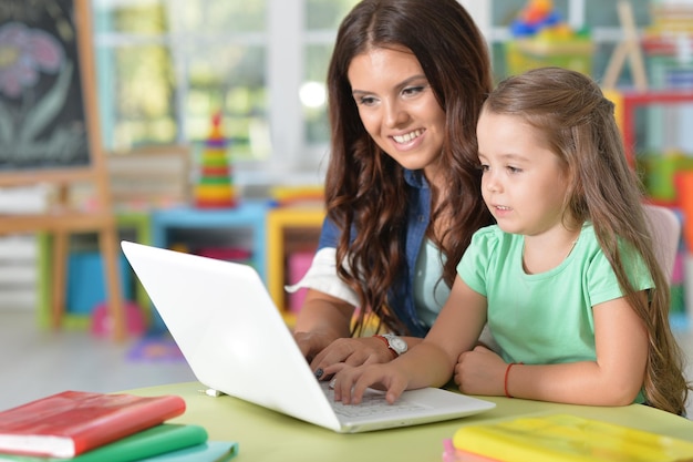 Retrato de mãe e filha felizes usando laptop na sala de jogos