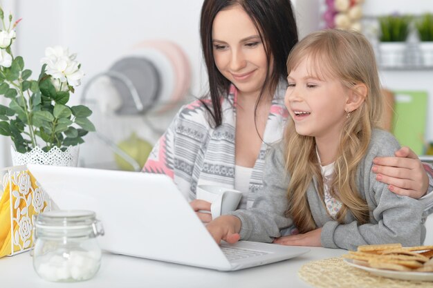 Retrato de mãe e filha felizes usando laptop