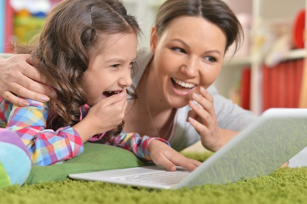 Retrato de mãe e filha felizes usando laptop