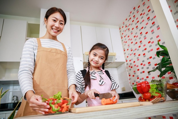 Retrato de mãe e filha gostam de preparar salada juntos na cozinha em casa