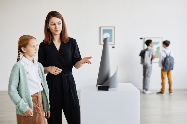 Retrato de mãe e filha olhando esculturas na galeria de arte moderna, copie o espaço