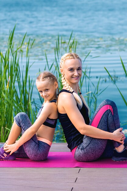 Retrato de mãe e filha sentadas em um tapete de ioga