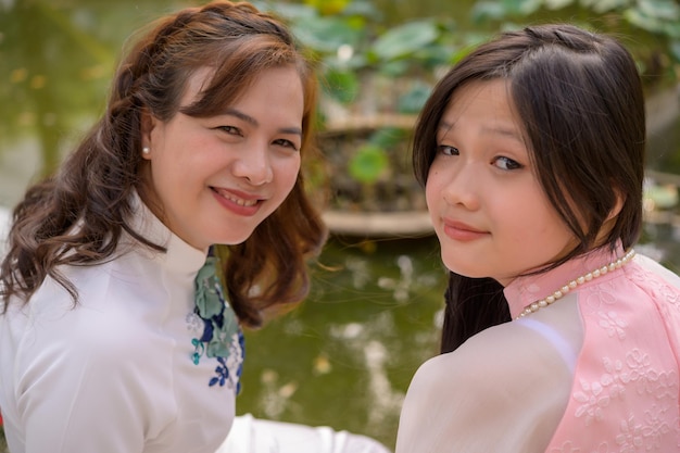 Retrato de mãe e filha vietnamitas em ao dai vestido tradicional vietnamita ao ar livre