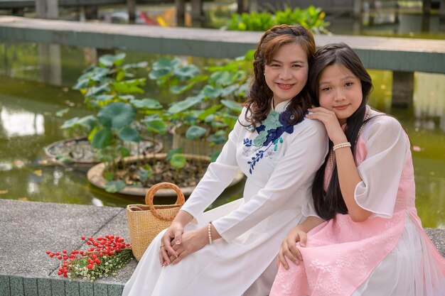 Retrato de mãe e filha vietnamitas em ao dai vestido tradicional vietnamita ao ar livre