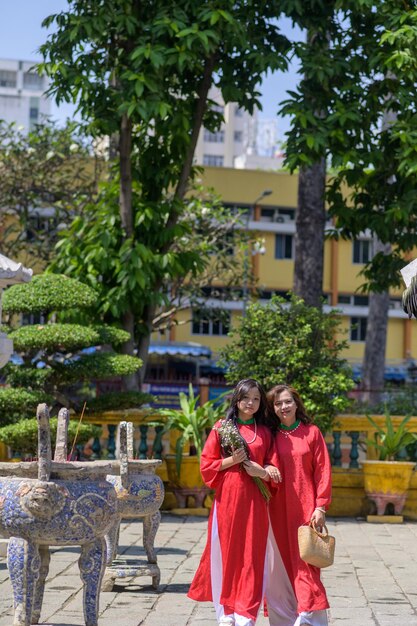 Foto retrato de mãe e filha vietnamitas em vestido vermelho ao dai visitam o pagode no feriado de tet