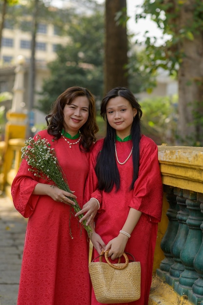Retrato de mãe e filha vietnamitas em vestido vermelho Ao Dai visitam o pagode no feriado de Tet