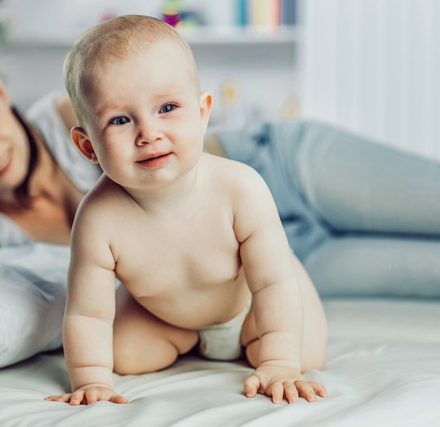 Retrato de mãe feliz e bebê de um ano na cama na cama