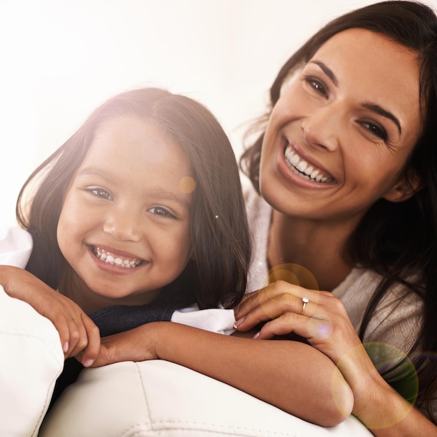 Foto retrato de mãe feliz e criança no sofá por amor, ligação ou cuidado com lente flare em casa rosto de mãe, pai ou menina, filha ou criança com sorriso na sala de estar para fim de semana familiar ou apoio