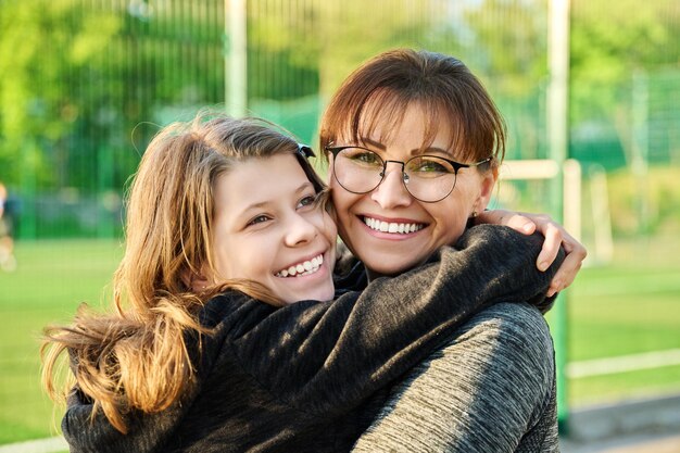 Retrato de mãe feliz e filha pré-adolescente se abraçando ao ar livre