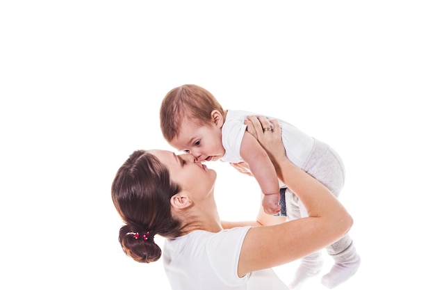 Retrato de mãe feliz e filho, abraçando bochecha em um fundo branco. Mãe de olhos fechados segurando a mão do bebê