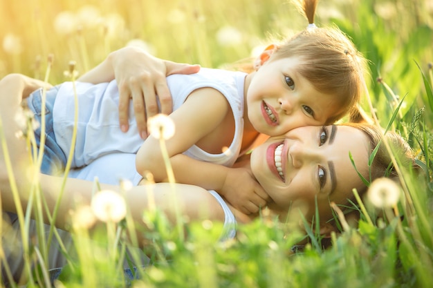 Retrato de mãe feliz e seu filho pequeno na primavera. Família alegre no campo-leão. Mãe e filha ao ar livre.