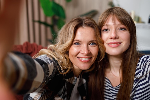 Retrato de mãe fofa e filha adulta que toma selfie em casa