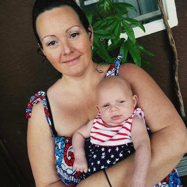 Foto retrato de mãe sorridente carregando bebê contra a parede