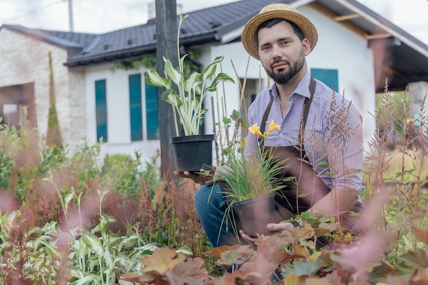 Retrato de mangardener com planta perene nas mãos no centro de jardim