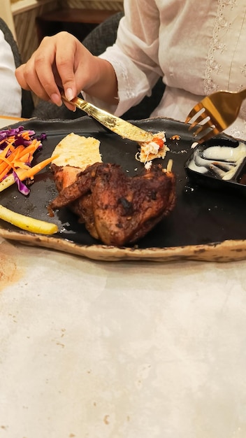 retrato de mãos de mulheres arranjando frango assado no forno e pão khubus pita uma comida árabe típica