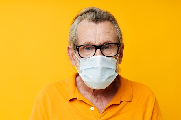 Retrato de máscara médica de homem idoso na proteção facial closeup fundo amarelo