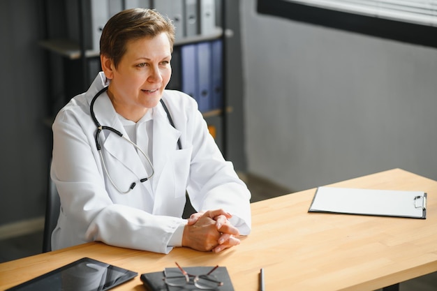 Retrato de médica madura de jaleco branco no local de trabalho