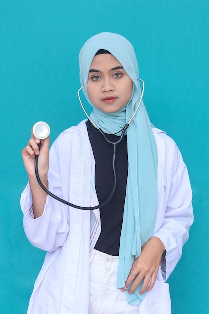 Retrato de médica muçulmana asiática mostrando estetoscópio para a câmera