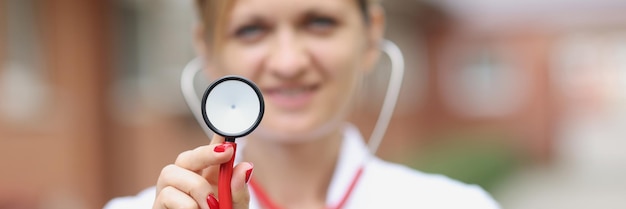 Retrato de médica sorridente segurando o estetoscópio. Conceito de serviços médicos de cardiologia